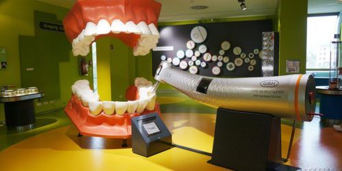 A kids play room with a giant set of oversized teeth and a giant drill for them to play with.
