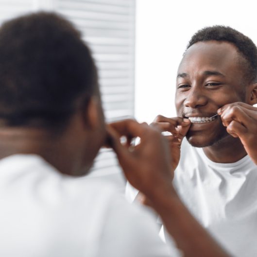 Man flossing his teeth for preventing Tooth Decay