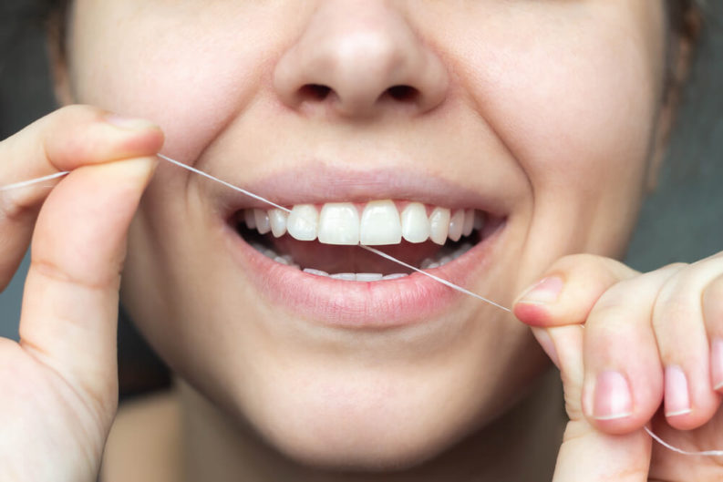 Woman using flossing her teeth for preventing Tooth Decay