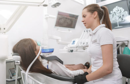 Dentist talking with her patient after putting her the sedation mask on