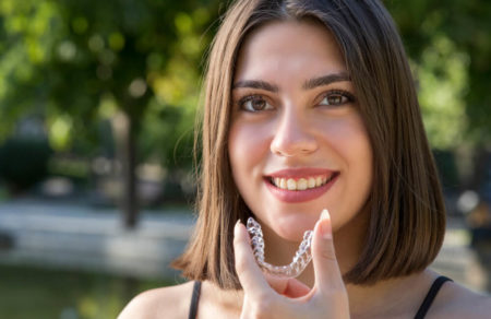 Woman placing her invisalign braces in her mouth