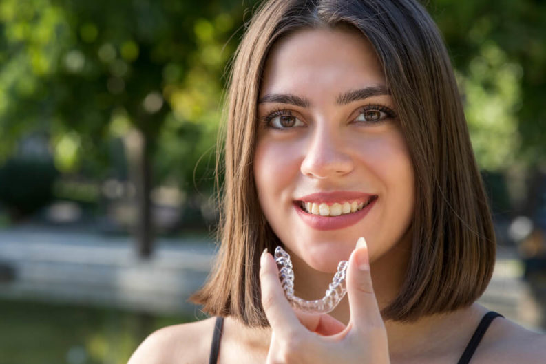 Woman placing her invisalign braces in her mouth