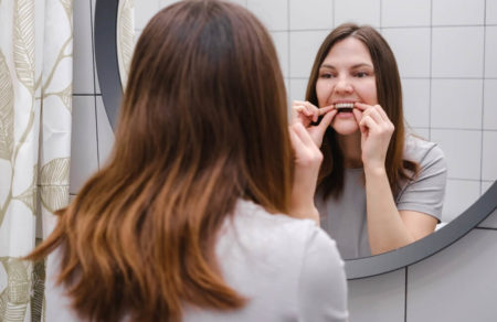 Woman in the bathroom placing invisalign braces after cleaning them