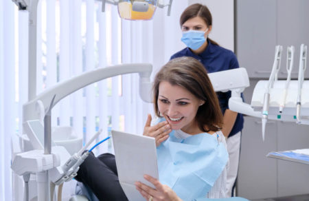 Woman holding a mirror appreciating the job performed at the dentist