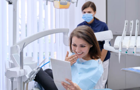 Woman holding a mirror appreciating the job performed at the dentist