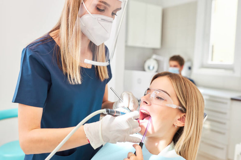 dentist performing a dental cleaning on patient