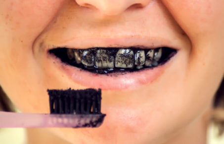 person brushing teeth with charcoal