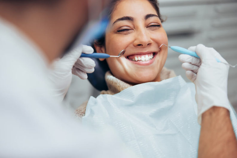 Woman smiling while getting teeth checked by the dentist