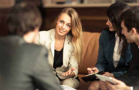 Woman at job interview smiling at small group of interviewers