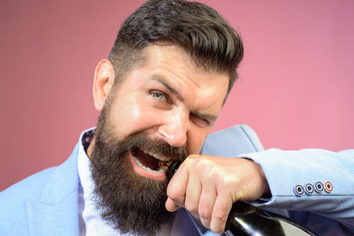 Man taking cork out of bottle with his teeth